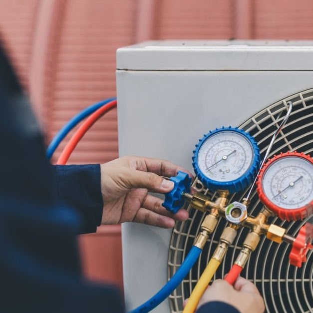 Technician is checking air conditioner. Air conditioning, HVAC service technician using gauges to check refrigerant and add refrigerant.
